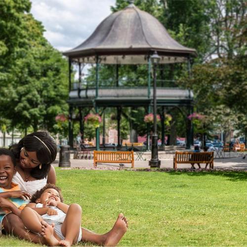 Family of three sitting on grass at Kings Square park Saint John