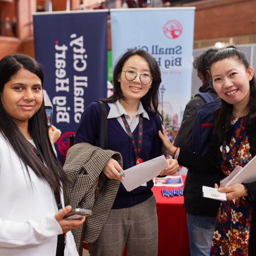 Three people standing together smiling at a career fair